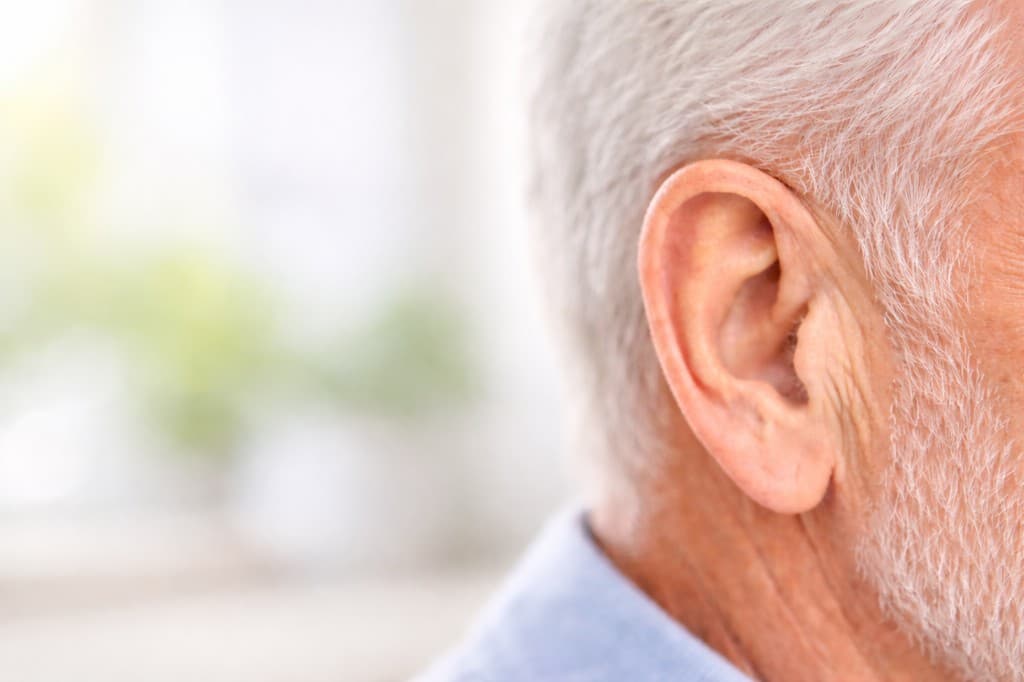 Крупний план вуха зі слуховим апаратом — налаштування у центрі слуху «Почути Все»